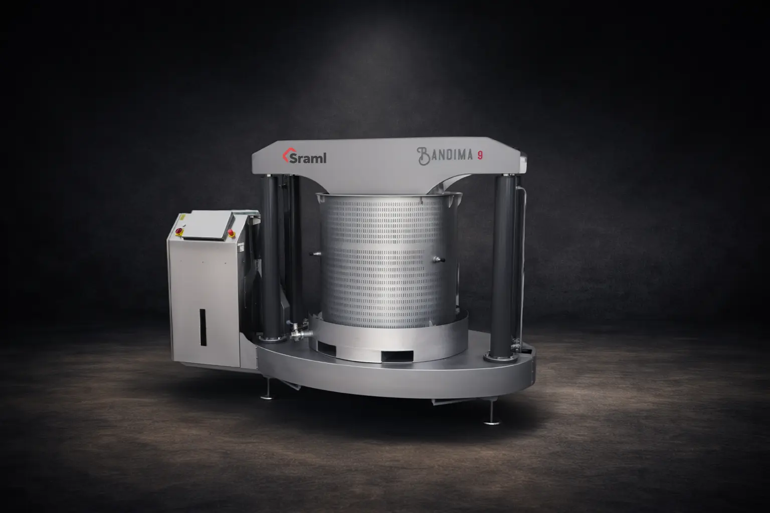Industrial metal processing machine with a perforated cylindrical drum on a circular base and a control cabinet to the left (Bandima 9 branding visible).