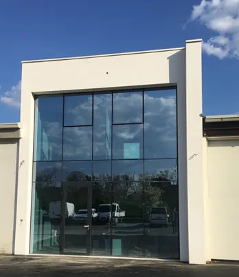 Modern glass storefront with tall entry doors, white facade, and blue sky above